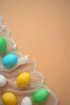 Vertical photo with painted Easter eggs on lace against background of peach.. Stock Photos
