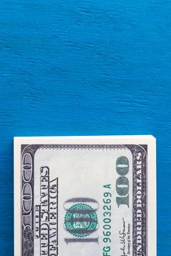 Vertical photo of a stack of hundred-dollar bills on a blue background with c Foto stock