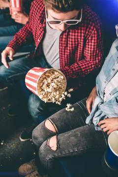 Vertical picture of guy looking at the basket of popcorn that is falling aside 库存照片