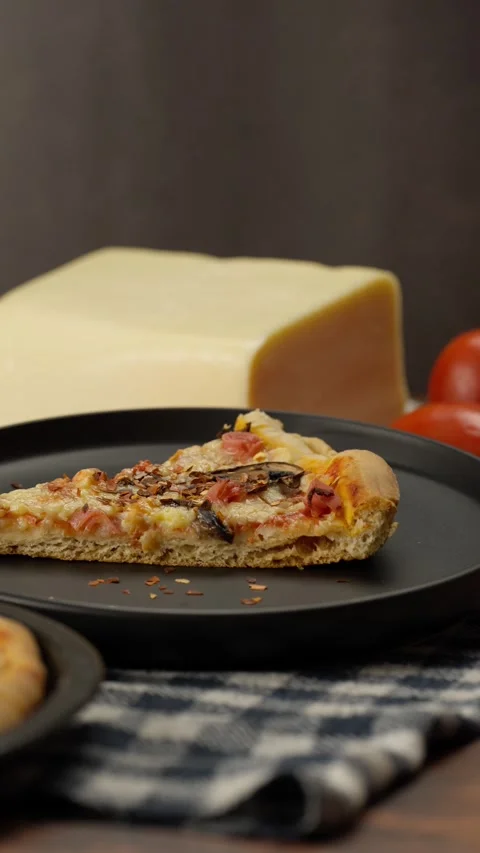 Vertical pizza, Crushed red pepper flakes falling onto a slice of pizza Stock Footage 282564663