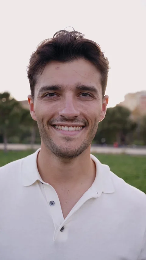 Vertical portrait of attractive smiling young man looking at camera in park Stock Footage 245744587