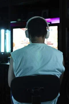 Vertical portrait of the back view of a gamer with headphones playing online Stock Photos