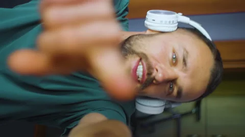 Vertical portrait bearded man funny dancing in wireless headphones and waving Stock Footage 168699846