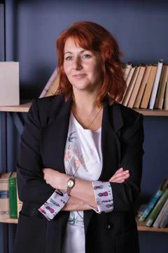 Vertical portrait of a beautiful red-haired woman in a blue jacket against th Stock Photos