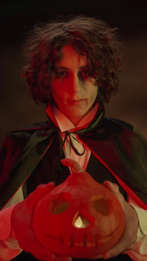 Vertical Portrait of Boy Dressed as Vampire Holding Carved Halloween Pumpkin Stock Footage 341672176