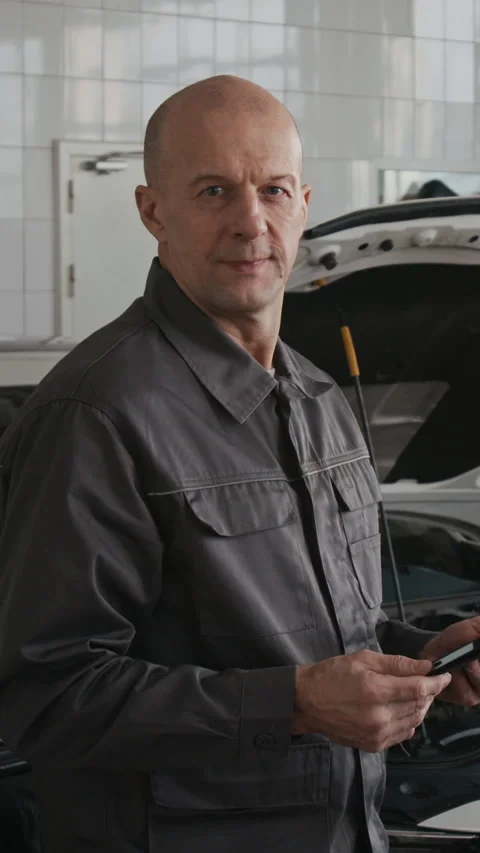 Vertical Portrait of Confident Mechanic with Tablet Testing Car Engine in Garage Stock Footage 329440408