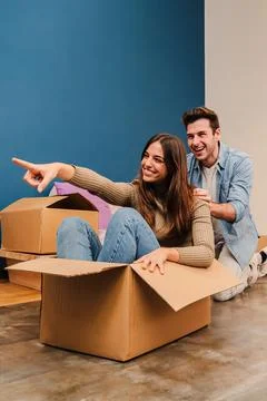 Vertical portrait of a couple playing while unpacking in their new apartment Stock Photos