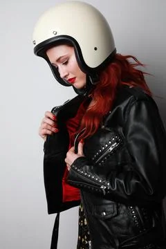 Vertical portrait of happy young biker woman wears helmet and leather jacket. Фото