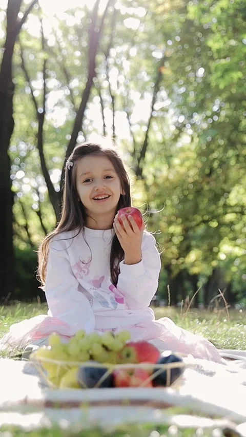 Vertical portrait of kid eating fruit. Small girl eats red apple bites and chews Stock Footage 268747430