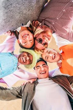 Vertical portrait. Low angle view of young multiracial friends smiling and Stock Photos
