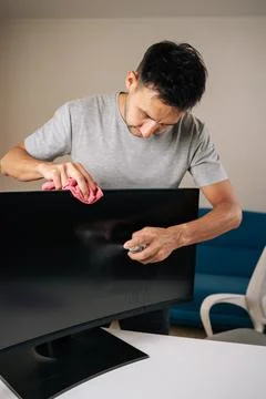 Vertical portrait of man cleaning computer monitor screen using disinfectant Stock Photos