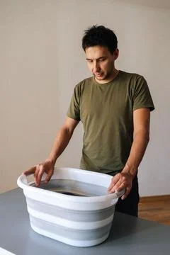 Vertical portrait of man preparing to housework, washing clothes by hand or Stock Photos