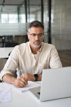 Vertical portrait of middle-age Hispanic man using laptop for business studying Stock Photos
