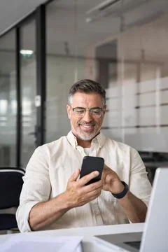 Vertical portrait of middle aged Hispanic business using cell phone mobile app. Stock Photos