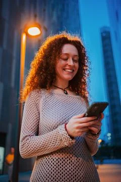 Vertical portrait of one female using a cellphone at nigh time. Young adult Stock Photos