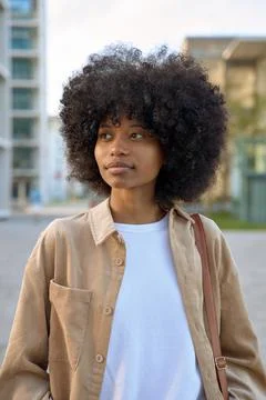 A vertical portrait of a smart student looking aside standing outdoors. Stock Photos