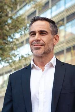 Vertical portrait of a smiling middle-aged businessman standing outdoors. Stock Photos