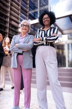 Vertical portrait two smiling multiethnic businesswomen posing for the camera. Stock Photos