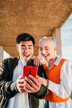 Vertical portrait of young couple using a cellphone to watch on the social media Stock Photos