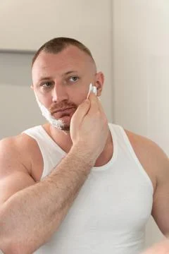 Vertical portrait of young man applying shaving foam before shaving Foto stock