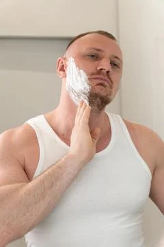 Vertical portrait of young man applying shaving foam before shaving Stock-Fotos