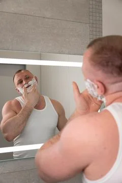 Vertical portrait of young man applying shaving foam before shaving Fotos de archivo