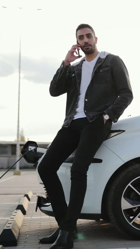 Vertical portrait of young Middle Eastern male talking on mobile phone charging Stock Footage 275011962