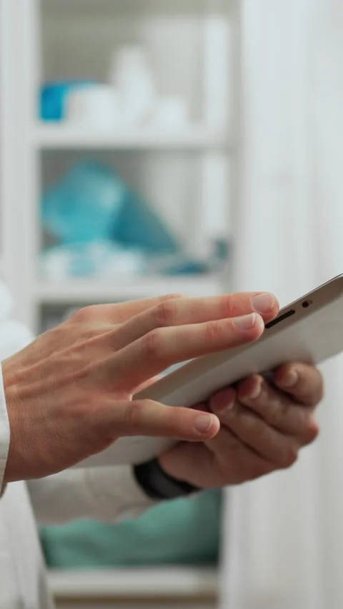 Vertical position. A medical expert in a white coat holds a tablet and exami Stock Footage 283268632
