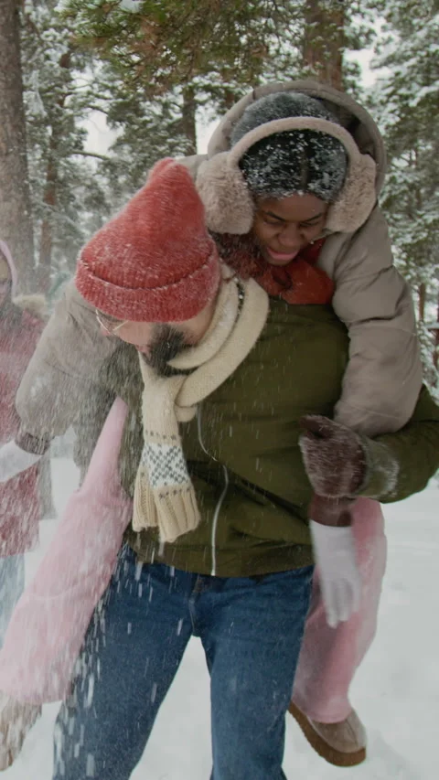 Vertical of Positive Guy Giving Piggyback Ride to Joyful Girl in Snowy Woods Stock Footage 333254941