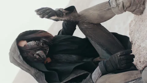 Vertical post apocalyptic female wanderer hand pouring sand sitting in desert Video stock 166756912