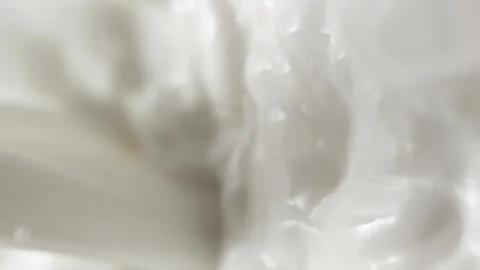 Vertical pouring white milk, close-up splashing fresh drink with drops and foam Stock Footage 250309756