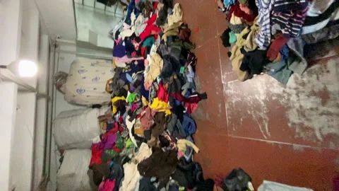 Vertical POV going through big piles of used clothes recycling Stock Footage 242424031