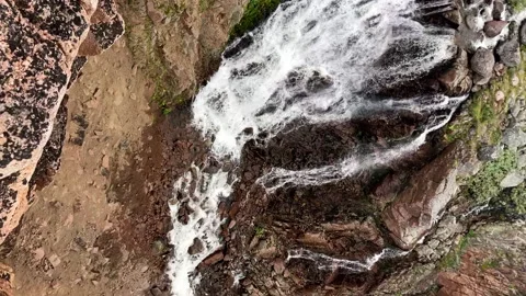 Vertical: POV of looking at a splashing small waterfall from the edge of cliff Stock Footage 233342039