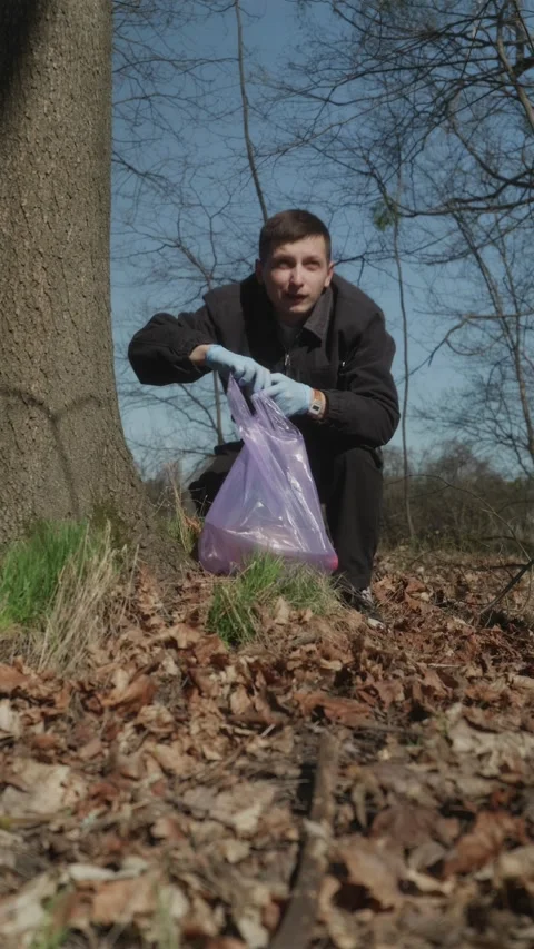 Vertical POV man picking up bottle into purple trash bag Stock Footage 333118407