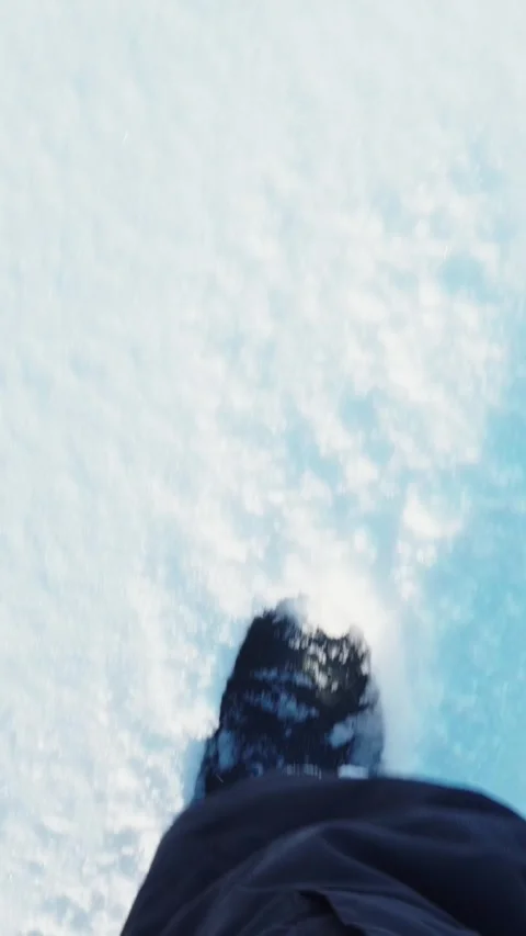 Vertical POV shot of walking in boots on thick snow and ice surface Stock Footage 346396912