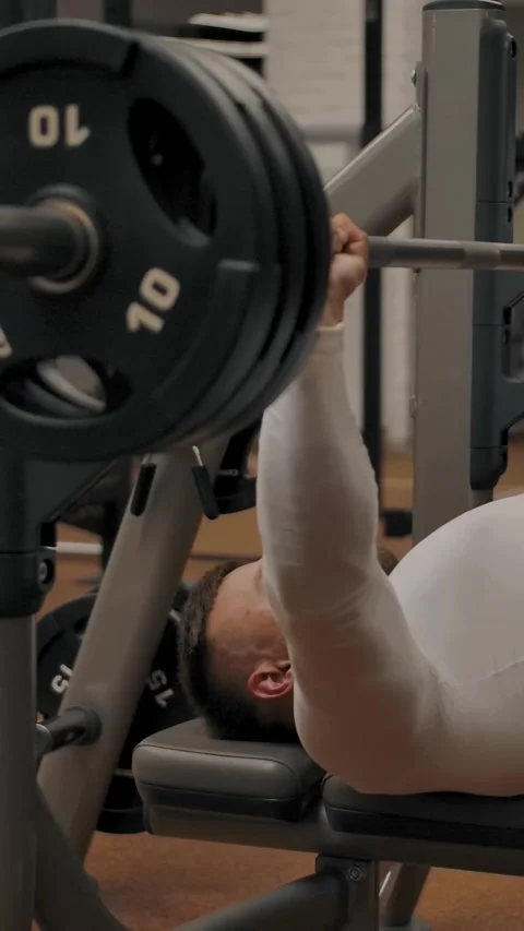 Vertical of Powerful male does a bench press with a barbell lying on a bench Stock Footage 276921910