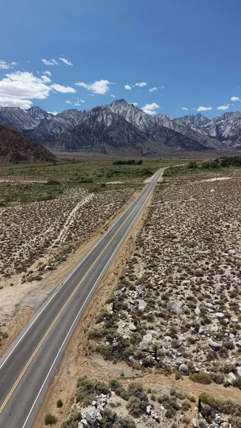 Vertical Pullback From Desert Road to Sierra Peaks, Sagebrush and Red Hills Stock Footage 338164627