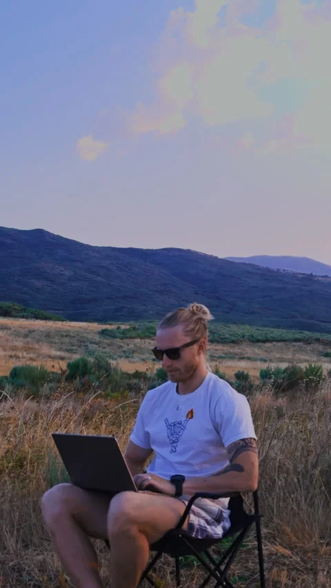 Vertical Rack Focus on Mountains with Blurred Man on Laptop Vídeos de archivo 345717023