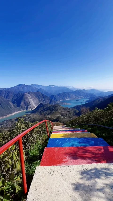 Vertical Rainbow Stairs Overlooking Blue Lake And Mountains 库存影片 334016936