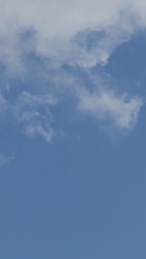 Vertical real-time footage of wispy white clouds drifting in a solid blue sky Stock Footage 342043871