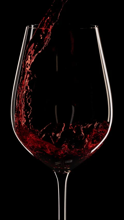 Vertical red wine pouring into wine glass, black background, slow motion Stock Footage 270481192