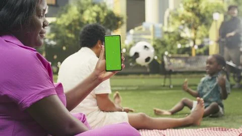 Vertical replaceable green screen on smartphone dominates picnic scene Stock Photos