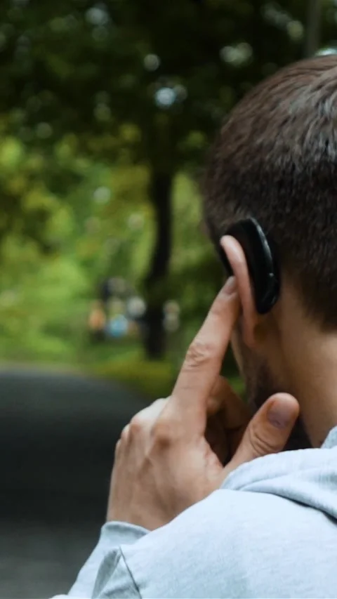 Vertical of Road runner talking by phone with bluetooth headset in autumn park. Stock Footage 278482782