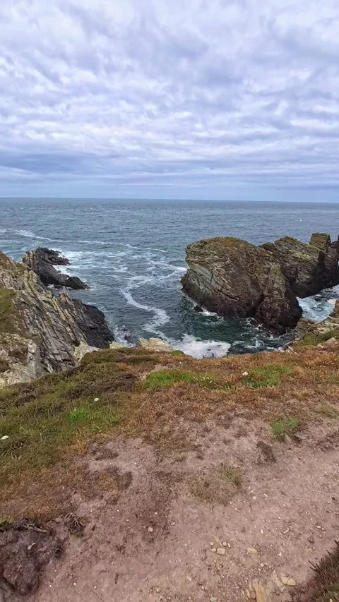 Vertical rocky welsh coastline overlooking the Irish sea on overcast day Видео 337924399