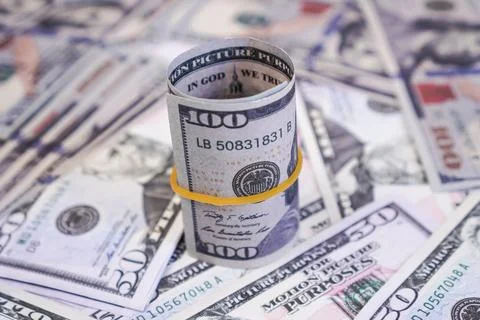 A vertical rolled stack of one hundred US dollar banknotes tied with a yell.. Stock Photos