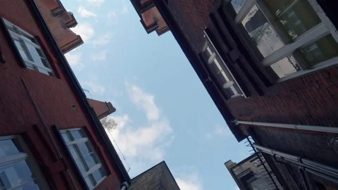 Vertical rotating shot looking up through buildings towards blue sky Stock Footage 148622993