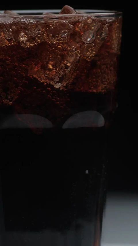 Vertical rotation macro shot  of Cola Bubbles and Ice Cubes in a Glass. 動画素材 141808233