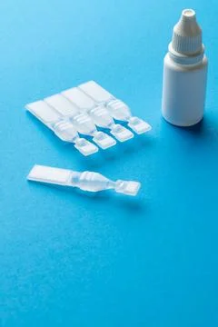 Vertical of saline solution caplets and dropper bottle on blue background with Stock Photos