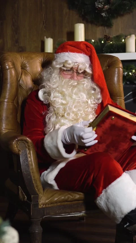 Vertical of Santa Claus pulling out old red silk album near christmas tree with Stock Footage 305515965