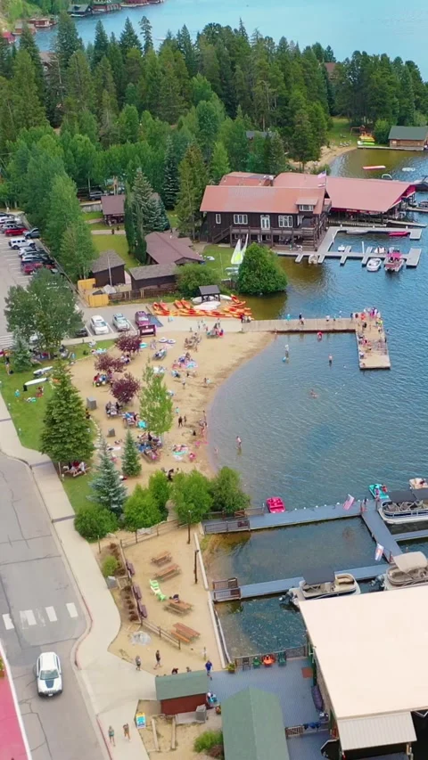 Vertical scenic drone view of a lakeside public beach featuring swimmers Stock Footage 334105075